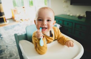 Smiling baby chewing spoon