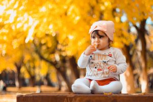 Baby eating sat on bench in park