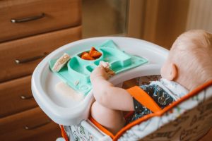 Baby in hi-chair with healthy food