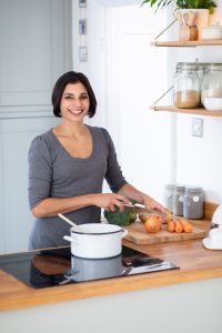 Female chef in kitchen with pan and vegetables